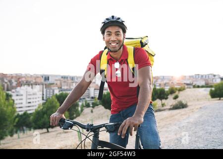 Homme souriant liveur portant un casque assis sur un vélo Banque D'Images