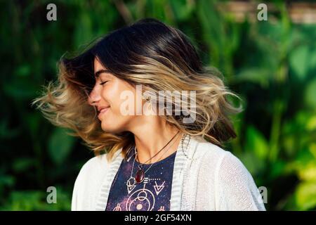 Jeune femme souriant tout en jetant les cheveux Banque D'Images