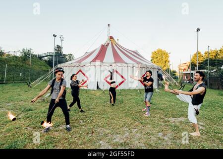 Artistes de cirque pratiquant avec des équipements d'incendie tout en se tenant sur la prairie Banque D'Images