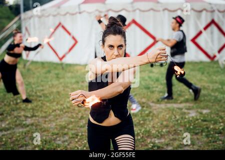 Femme acrobat pratiquant avec l'équipement d'incendie à l'extérieur de la tente de cirque Banque D'Images