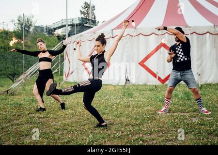 Artistes masculins et féminins pratiquant devant une tente de cirque Banque D'Images