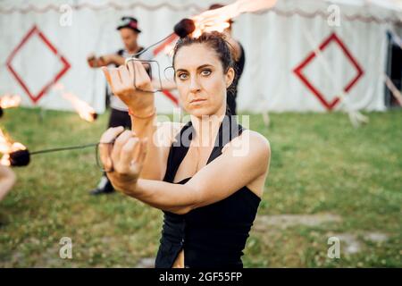 Artiste femme tenant des équipements de feu tout en pratiquant au cirque Banque D'Images