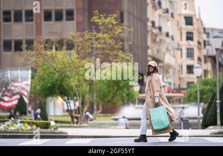 Jeune femme avec des sacs de shopping marchant sur la route en ville Banque D'Images