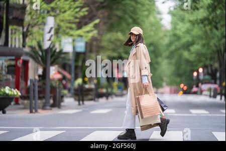 Jeune femme avec des sacs de shopping marchant sur la route Banque D'Images