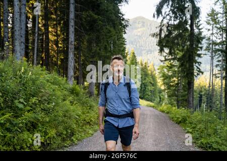 Homme avec sac à dos sur la route au milieu des arbres Banque D'Images