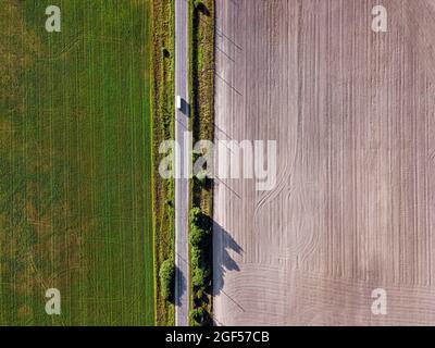 Vue aérienne de la conduite de bus le long de la route de campagne séparant deux champs agricoles Banque D'Images