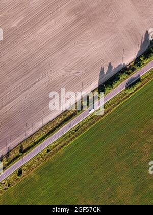 Vue aérienne de la conduite de bus le long de la route de campagne séparant deux champs agricoles Banque D'Images