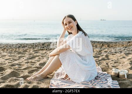 Bonne belle femme assise sur une serviette de plage Banque D'Images