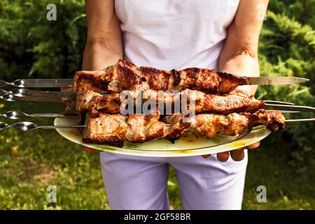 Femme tenant des kebabs frits cuits. Les morceaux de viande juteux sont Bravo. Banque D'Images