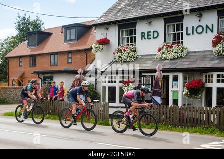 Les cyclistes qui participent à la course sur route Victor Berlemont Trophy 2021 autour de Woodcote dans l'Oxfordshire passent devant la maison publique Red Lion à Woodcote Banque D'Images