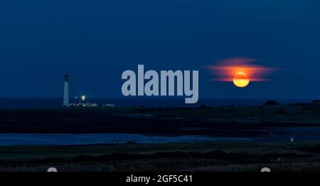 Dunbar, East Lothian, Écosse, Royaume-Uni, 23 août 2021. Météo au Royaume-Uni : lever de lune. Une vue de la pleine lune d'août connue sous le nom de lune d'esturgeon ce soir au-dessus de l'horizon dans le ciel de nuit au phare de Barns Ness. Banque D'Images