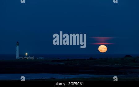 Dunbar, East Lothian, Écosse, Royaume-Uni, 23 août 2021. Météo au Royaume-Uni : lever de lune. Une vue de la pleine lune d'août connue sous le nom de lune d'esturgeon ce soir au-dessus de l'horizon dans le ciel de nuit au phare de Barns Ness. Banque D'Images