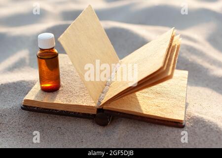 Livre de recettes vierge pour la préparation de plantes médicinales naturelles. Bouteille sur sable. Banque D'Images