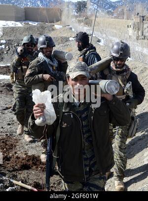 Les membres des Forces de sécurité nationale afghanes de l'unité d'intervention du village de Paktika, ou VRU, portent quatre roquettes de 107 mm trouvées lors d'une opération, le 19 janvier 2014, dans le village de Nawiquala, dans le district de Sarobi, Province de Paktika. (É.-U. Photographie de l'armée par Sgt. Jared Gehmann/ libéré) Banque D'Images