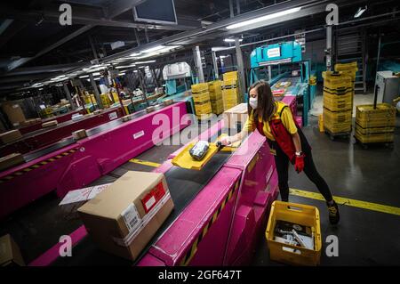 19 août 2021, Baden-Wuerttemberg, Köngen: Adriana TEC, répartiteur au centre de colis DHL à Köngen, place des colis sur une ligne de montage pendant son quart de nuit (à dpa: "Grand volume de colis au centre de distribution DHL - Corona or Not") photo: Christoph Schmidt/dpa Banque D'Images