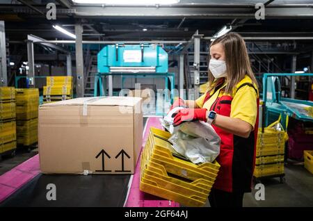 19 août 2021, Baden-Wuerttemberg, Köngen: Adriana TEC, répartiteur au centre de colis DHL à Köngen, place des colis sur une ligne de montage pendant son quart de nuit (à dpa: "Grand volume de colis au centre de distribution DHL - Corona or Not") photo: Christoph Schmidt/dpa Banque D'Images