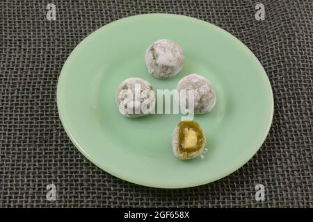 Mochi de thé vert avec garniture crémeuse sur une assiette à collation verte sur un toile de jute grise Banque D'Images