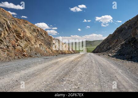 Vue sur la route, les montagnes et le ciel avec les nuages depuis le col de montagne d'Obotyn-Daba. Chemin vers Bayan-Ulgii en Mongolie occidentale. Banque D'Images