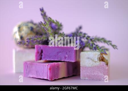 Savon de lavande et bombes de bain, branches de lavande sur fond violet clair. Concept de cosmétiques végétaliens. Cosmétiques biologiques à base de plantes avec extrait de lavande Banque D'Images