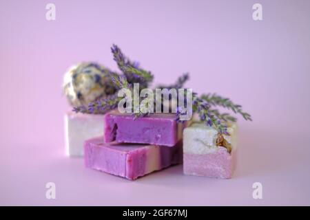 Savon de lavande et bombes de bain, brins de lavande sur fond violet clair. Concept de cosmétiques respectueux de l'environnement végétalien. Produits de beauté biologiques à base de plantes avec Banque D'Images