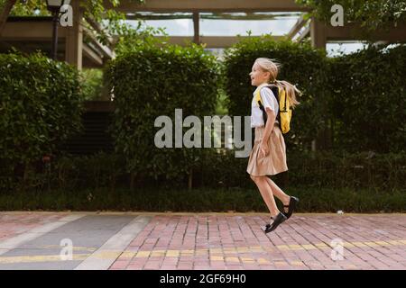 Écolière de retour à l'école après les vacances d'été. Enfant en uniforme souriant tôt le matin à l'extérieur. Banque D'Images