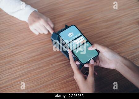 Une femme qui paie sa facture par application bancaire en ligne sur son smartphone dans un centre commercial. Banque D'Images