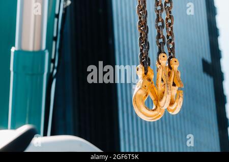 Les crochets de la grue mobile près de la vitre de bâtiments élevés.beaucoup de crochets suspendus à des chaînes suspendues à une grue. Banque D'Images