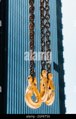 Les crochets de la grue mobile près de la vitre de bâtiments élevés.beaucoup de crochets suspendus à des chaînes suspendues à une grue. Banque D'Images