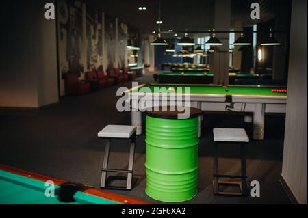 table et deux chaises près de la table de billard couverte de verdure avec des boules dans le club de billard. Banque D'Images