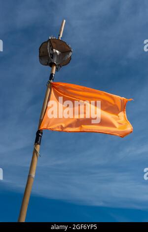 Un drapeau de marqueur de filet de pêche orange agitant dans un vent élevé. La photo a été prise dans de bonnes conditions d'éclairage. Milieu de la journée, ciel bleu. Banque D'Images