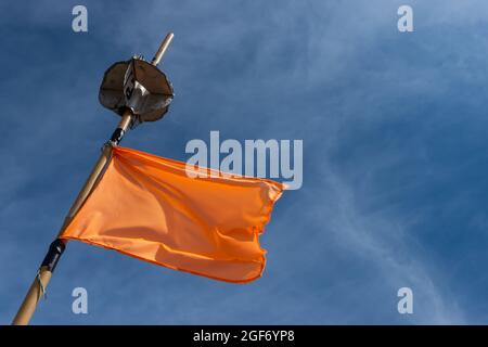 Un drapeau de marqueur de filet de pêche orange agitant dans un vent élevé. La photo a été prise dans de bonnes conditions d'éclairage. Milieu de la journée, ciel bleu. Banque D'Images