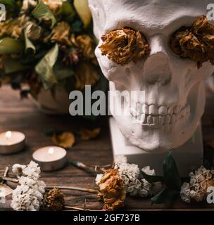 Un bouquet de fleurs sauvages avec des bougies sur la table et un crâne. Banque D'Images