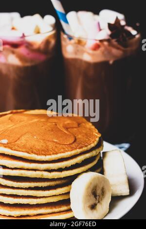 Crêpes avec du miel et des tranches de banane sur fond de doux cocktails. Petit-déjeuner le matin Banque D'Images