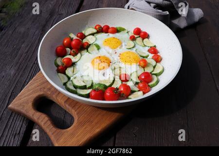 Petit déjeuner tardif, œufs frits avec courgettes, tomates cerises. Shakshuka dans une poêle sur fond rustique. Cuisine arabe. Nourriture casher. Banque D'Images