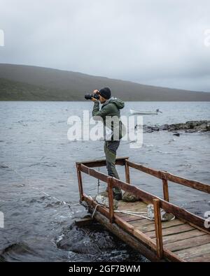 Randonneur photographié sur une passerelle en bois au-dessus du lac Leitisvatn, Vagar, îles Féroé Banque D'Images