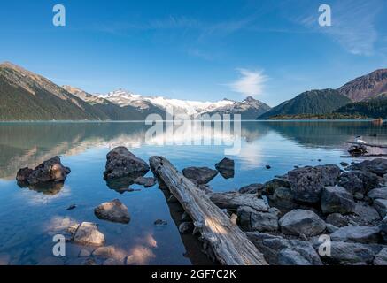Lac Garibaldi, troncs d'arbres sur la rive, montagnes reflétées dans le lac glaciaire turquoise, la montagne de la Garde et le pic de déception, glacier à l'arrière Banque D'Images
