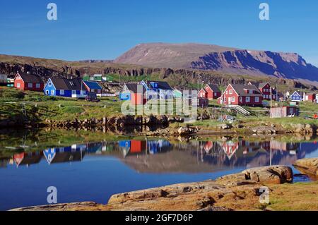 Maisons en bois reflétées dans l'eau, montagnes en arrière-plan, Qeqertarsuaq, île Disko, Artkis, Groenland, Danemark Banque D'Images