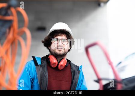 Un jeune ingénieur avec casque et contrôles de protection auditive à l'extérieur du lieu de travail, Fribourg, Bade-Wurtemberg, Allemagne Banque D'Images