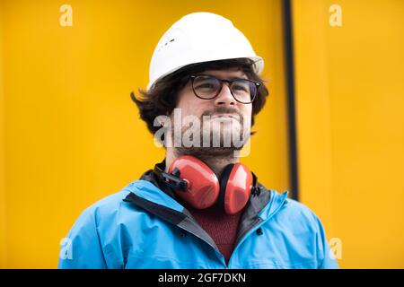 Jeune ingénieur équipé d'un casque et d'une protection auditive sur un site de travail à l'extérieur, Fribourg, Bade-Wurtemberg, Allemagne Banque D'Images