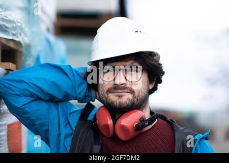 Jeune ingénieur équipé d'un casque et d'une protection auditive sur un site de travail à l'extérieur, Fribourg, Bade-Wurtemberg, Allemagne Banque D'Images