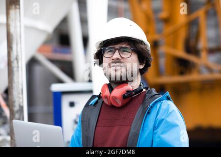 Jeune ingénieur portant un casque et une protection auditive sur un chantier de construction, Freiburg, Bade-Wurtemberg, Allemagne Banque D'Images