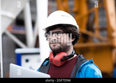 Jeune ingénieur portant un casque et une protection auditive sur un chantier de construction, Freiburg, Bade-Wurtemberg, Allemagne Banque D'Images