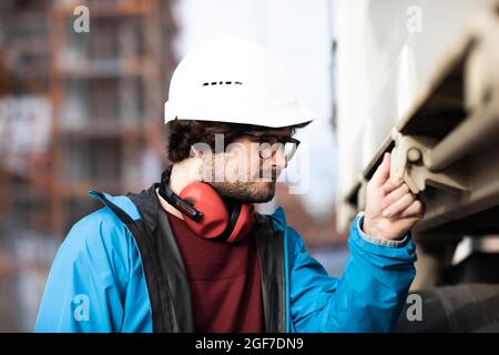 Jeune ingénieur portant un casque et une protection auditive sur un chantier de construction, Freiburg, Bade-Wurtemberg, Allemagne Banque D'Images