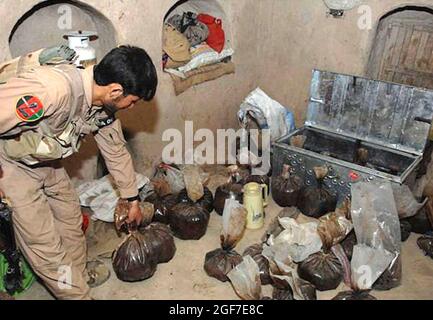 CACHE D'OPIUM un agent de la police nationale afghane inspecte une cache d'opium trouvée dans une maison de sécurité des Taliban, dans le village de Babaji, dans la province de Helmand, en Afghanistan, le 7 mai 2009. Photo : Cpl Sean Harp, Armée des États-Unis. Banque D'Images