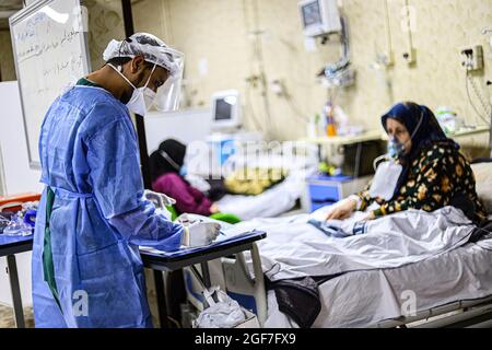 Idlib, Syrie. 18 août 2021. Un médecin vêtu d'une combinaison protectrice prend soin d'une femme âgée souffrant d'une mutation delta dans un hôpital isolé de la ville d'Idlib. Le mutant delta est arrivé à Idlib, où le génotypage a été effectué pour 92 échantillons dans le laboratoire Idlib. Le mutant alpha a été trouvé dans 6 échantillons, et le mutant delta a été trouvé dans 47 échantillons, et il y a une augmentation significative du nombre de cas confirmés de Covid-19 au cours des derniers jours. Crédit : SOPA Images Limited/Alamy Live News Banque D'Images