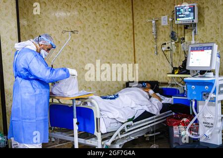 Idlib, Syrie. 18 août 2021. Un médecin vêtu d'un costume de protection prend soin d'un homme âgé dans un hôpital isolé de la ville d'Idlib. Le mutant delta est arrivé à Idlib, où le génotypage a été effectué pour 92 échantillons dans le laboratoire Idlib. Le mutant alpha a été trouvé dans 6 échantillons, et le mutant delta a été trouvé dans 47 échantillons, et il y a une augmentation significative du nombre de cas confirmés de Covid-19 au cours des derniers jours. Crédit : SOPA Images Limited/Alamy Live News Banque D'Images