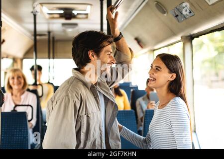 Beau couple souriant debout dans le bus et parlant Banque D'Images