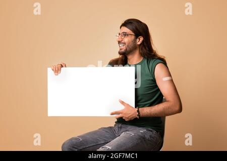 Homme vacciné gai du Moyen-Orient avec une planche vide Banque D'Images