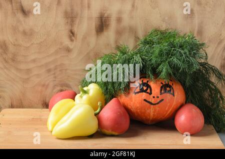 Citrouille drôle avec les yeux peints et un sourire sur un fond en bois dans la décoration de l'aneth et des légumes. Mise au point sélective. Banque D'Images