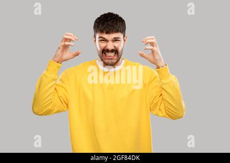 jeune homme en colère avec un sweat-shirt jaune sur le gris Banque D'Images